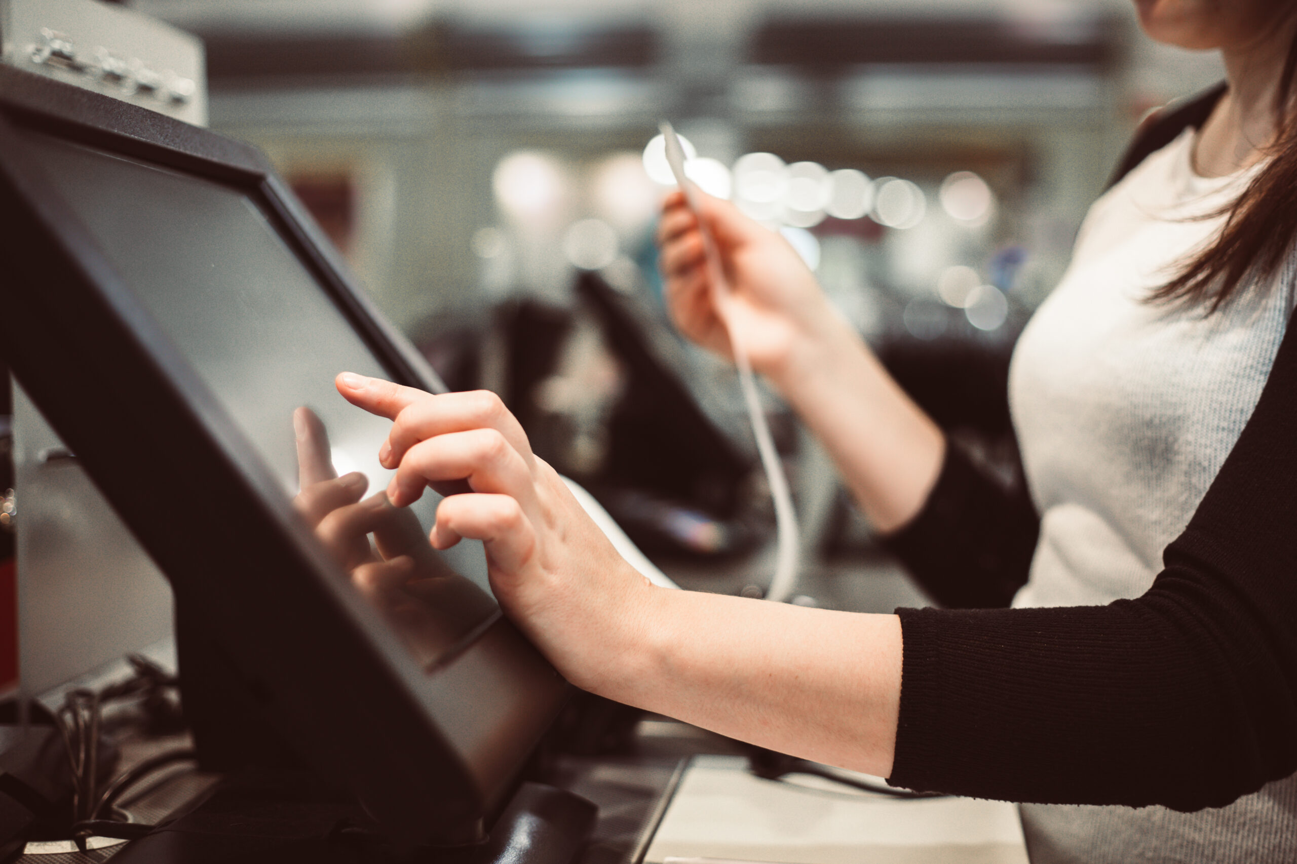 Young woman hand doing process payment on a touchscreen cash register, finance concept (color toned image)